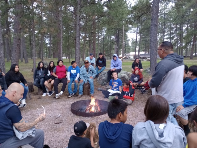 People sitting around the Campfire as Pastor Mark speaks to everyone.